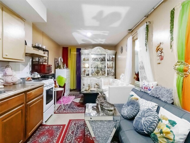 81-56 102nd Rd, Ozone Park, NY 11416 - kitchen with light countertops, white electric range oven, under cabinet range hood, and brown cabinets