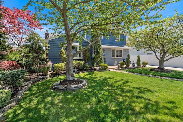 obstructed view of property with fence, a chimney, and a front lawn