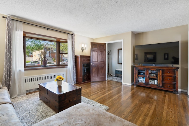 living area with a textured ceiling, radiator, and wood finished floors