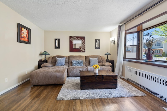 living area with a textured ceiling, dark wood-style floors, and radiator