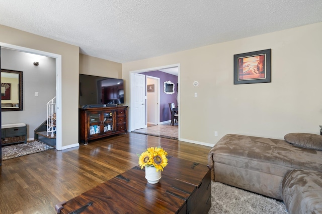 living area with stairs, a textured ceiling, baseboards, and wood finished floors