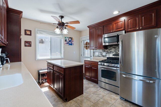 kitchen with a center island, light countertops, tasteful backsplash, a ceiling fan, and stainless steel appliances
