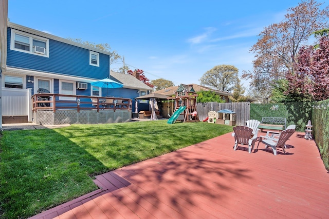 wooden terrace with a fenced backyard, a playground, a yard, and a wall mounted air conditioner