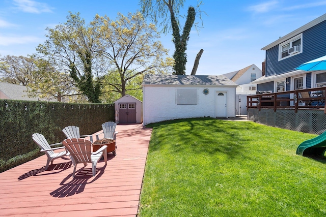 view of yard with a wooden deck, an outdoor structure, a playground, a fenced backyard, and a shed