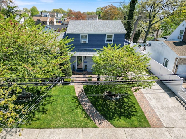 view of front of property with fence, a shingled roof, and a front lawn