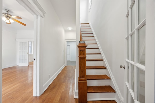 stairway with baseboards, a ceiling fan, and wood finished floors