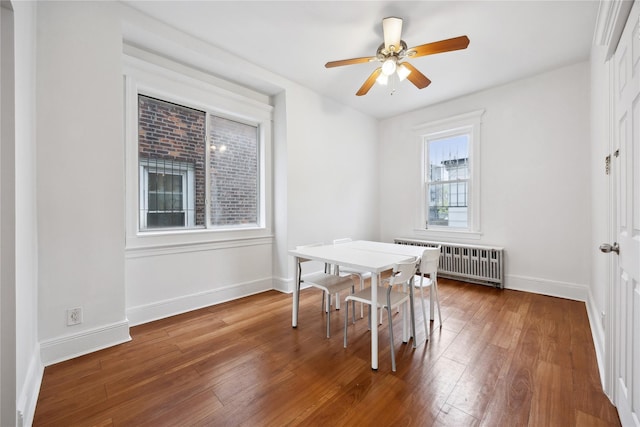 dining space featuring radiator heating unit, baseboards, ceiling fan, and wood finished floors