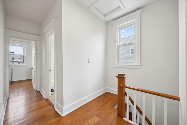hall with baseboards, an upstairs landing, attic access, and light wood-type flooring