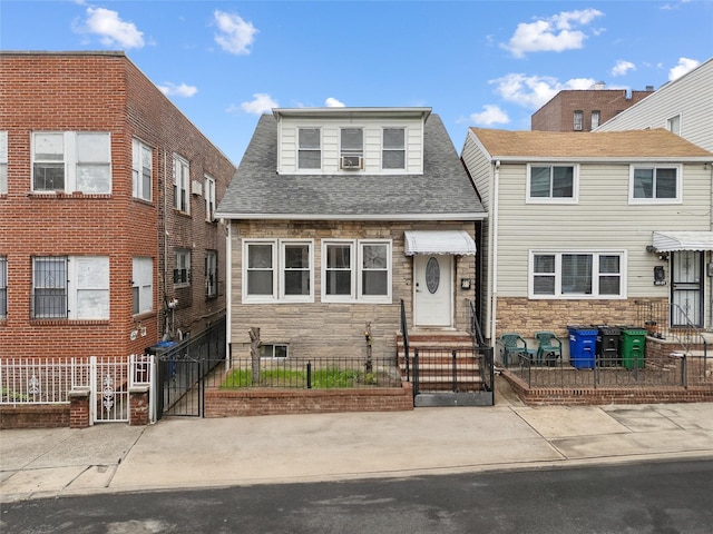 multi unit property featuring a gate, a fenced front yard, roof with shingles, and stone siding