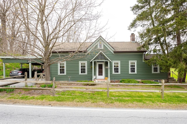 view of front of home with a chimney, fence private yard, and a carport