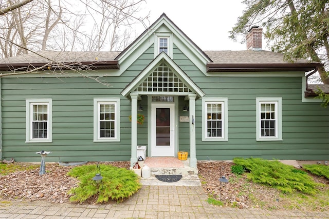 view of front of property with a shingled roof and a chimney