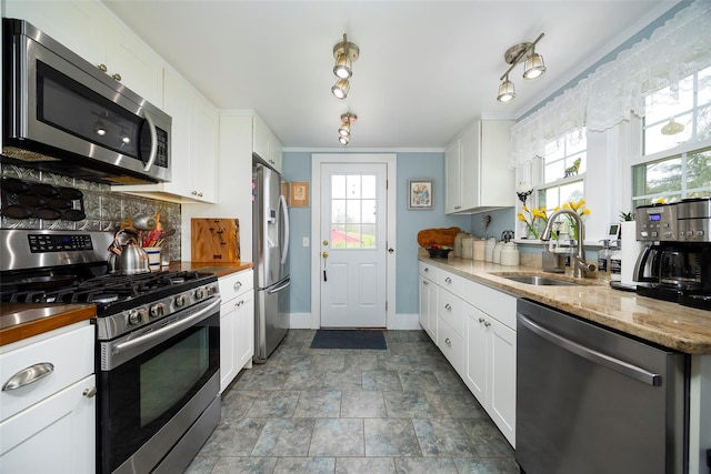 kitchen featuring backsplash, stainless steel appliances, white cabinets, and a sink