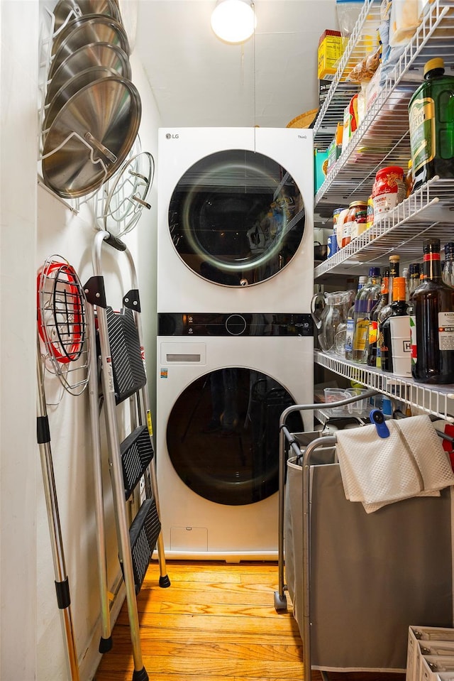 washroom featuring laundry area, wood finished floors, and stacked washer and clothes dryer