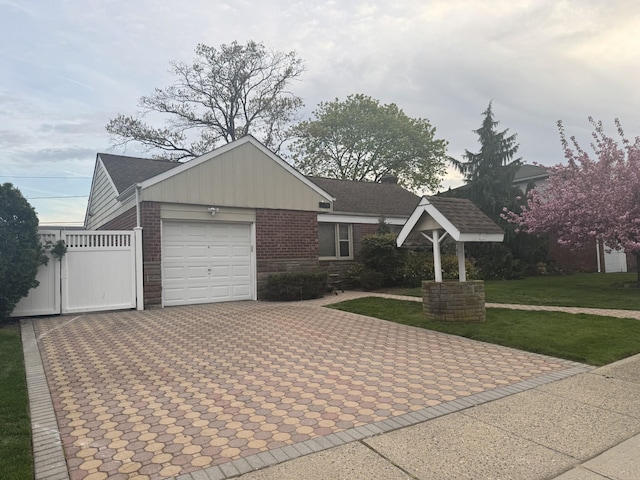 view of front of home with a garage, a front yard, decorative driveway, brick siding, and a gate