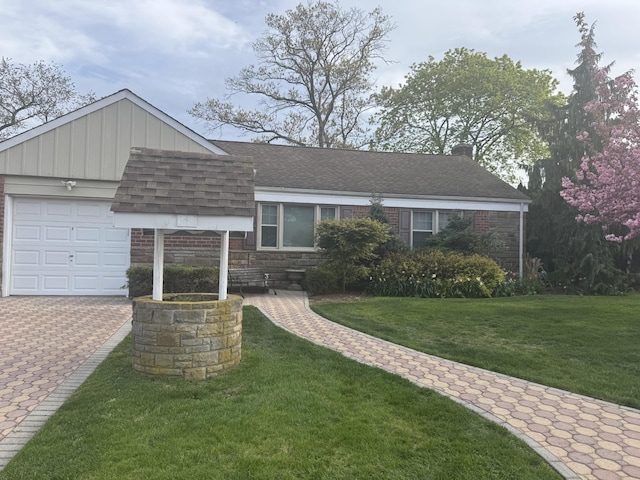 split level home with a front lawn, roof with shingles, a chimney, an attached garage, and driveway