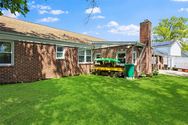 1037 Chestnut St, North Valley Stream, NY 11580 - rear view of property featuring a chimney, brick siding, and a yard