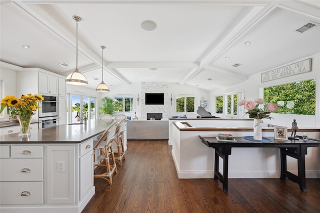 kitchen with vaulted ceiling with beams, dark wood-style flooring, visible vents, and dark countertops