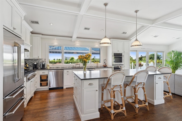 kitchen featuring coffered ceiling, backsplash, a breakfast bar, and stainless steel appliances
