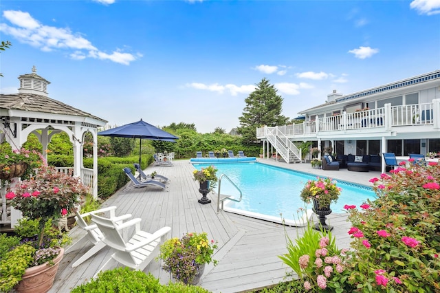 outdoor pool with a deck, a gazebo, stairs, and an outdoor hangout area