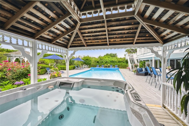 pool with stairs, a gazebo, and a hot tub
