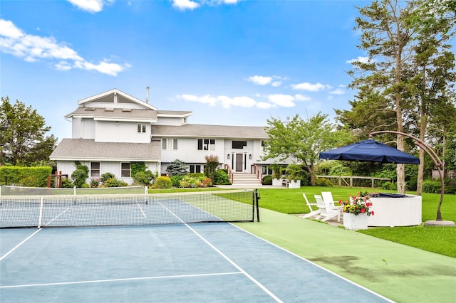 view of tennis court featuring fence and a yard