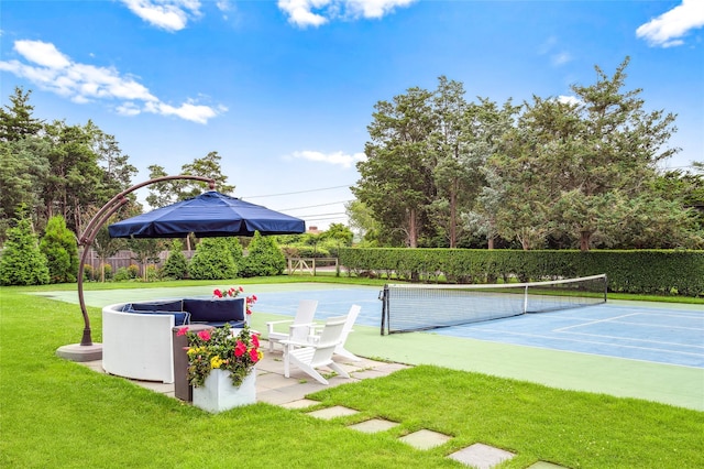 view of tennis court with a lawn and fence