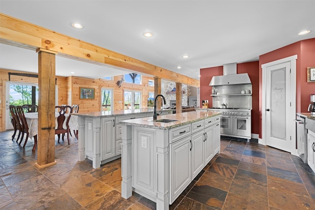 535 County Route 22, Middletown, NY 10940 - kitchen featuring wall chimney range hood, a sink, a kitchen island with sink, recessed lighting, and stone tile floors
