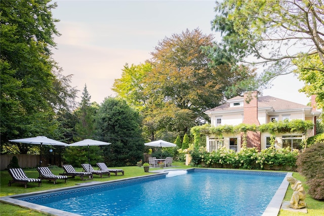 outdoor pool with fence and a yard