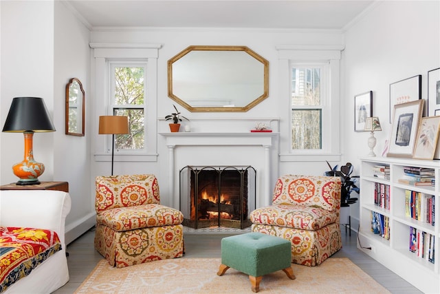 sitting room featuring crown molding, a fireplace with flush hearth, and wood finished floors