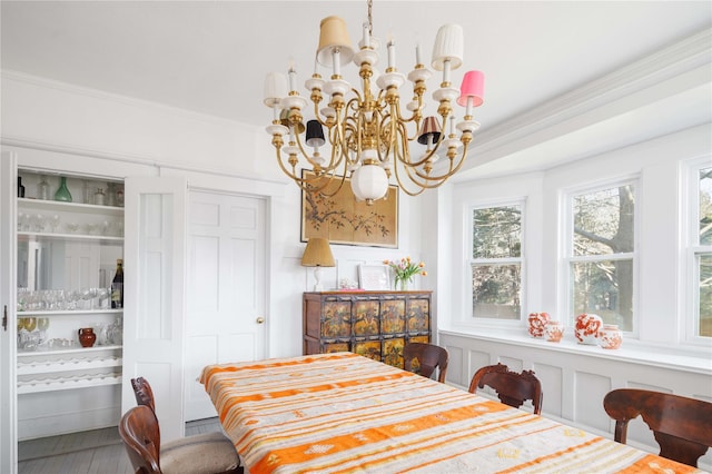 dining area with ornamental molding, wood finished floors, and a chandelier
