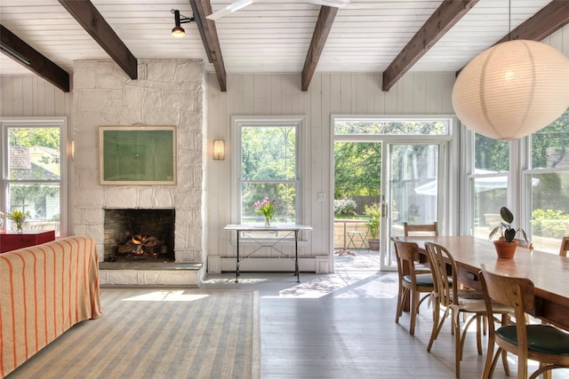 sunroom featuring beam ceiling, baseboard heating, and a healthy amount of sunlight