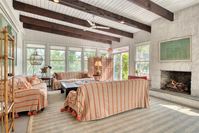 living room featuring beam ceiling, a fireplace, wood walls, a ceiling fan, and wooden ceiling