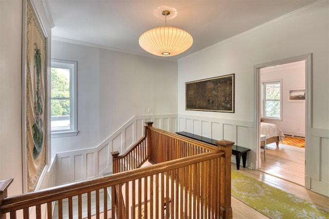 stairs featuring crown molding, wainscoting, and wood finished floors