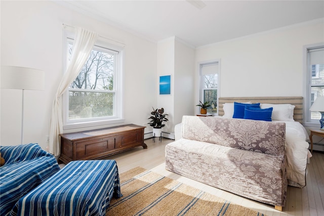sitting room with crown molding, a baseboard heating unit, plenty of natural light, and wood finished floors