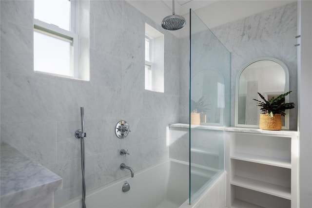 bathroom featuring a combined bath / shower with rainfall shower and a wealth of natural light