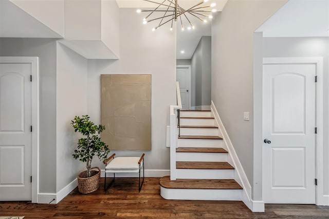 stairs with baseboards, wood finished floors, and a notable chandelier
