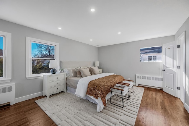 bedroom featuring baseboards, recessed lighting, radiator, and wood finished floors