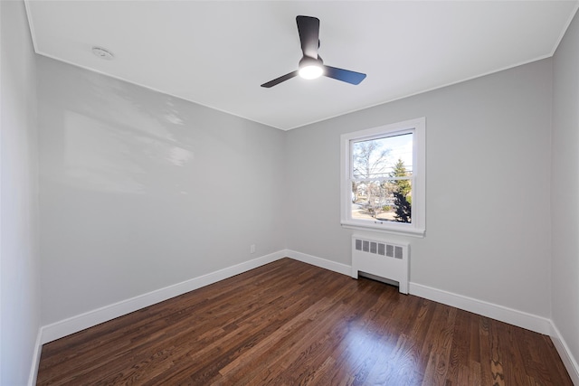 spare room with baseboards, a ceiling fan, dark wood finished floors, and radiator heating unit