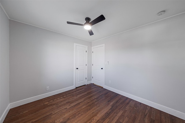 spare room featuring baseboards, ornamental molding, ceiling fan, and dark wood-style floors