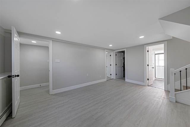 below grade area with light wood-style floors, recessed lighting, baseboards, and a baseboard heating unit