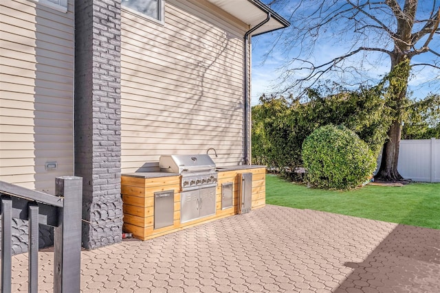 view of patio with an outdoor kitchen, fence, and a grill
