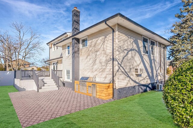 rear view of house featuring a deck, cooling unit, an outdoor kitchen, a patio area, and a yard