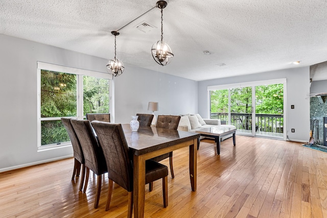 dining room with visible vents, a textured ceiling, a notable chandelier, and a healthy amount of sunlight