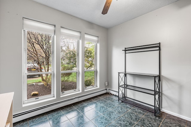 spare room with dark tile patterned floors, a ceiling fan, a textured ceiling, and baseboard heating