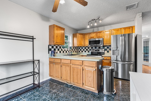 kitchen with light countertops, stainless steel appliances, a peninsula, decorative backsplash, and visible vents