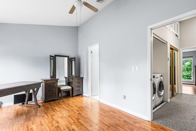 interior space featuring ceiling fan, laundry area, independent washer and dryer, a towering ceiling, and light wood finished floors
