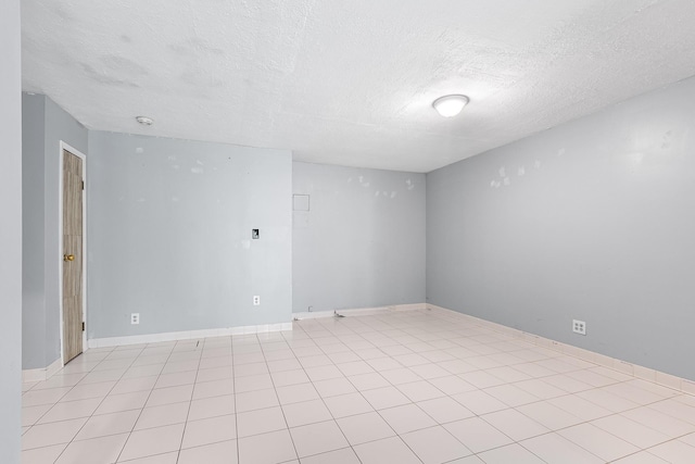 spare room featuring baseboards and a textured ceiling