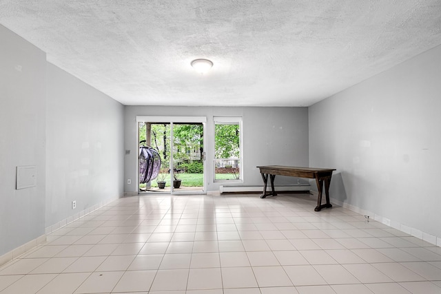 spare room with baseboards, baseboard heating, light tile patterned flooring, and a textured ceiling