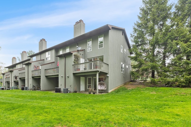rear view of house featuring a lawn, central AC, and a chimney