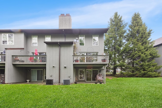 rear view of property featuring central AC, a yard, and a chimney